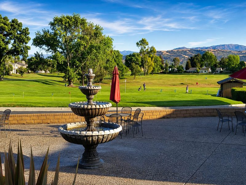 Outdoor patio with fountain, tables, umbrellas, and golf course views at Ridgemark Golf Club & Resort.