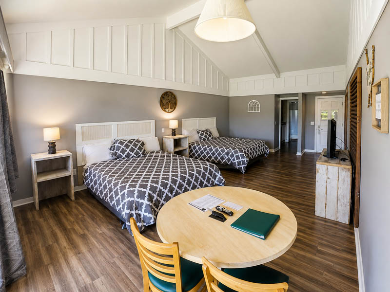 Large guest room with two beds, dining table, vaulted ceiling, and wood flooring at Ridgemark Golf Club & Resort.