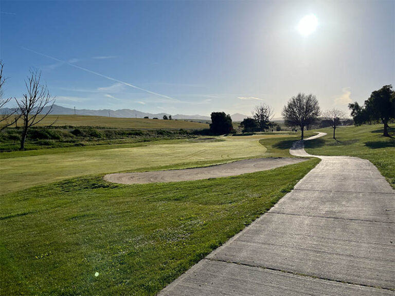 Fairway, sand bunker, and cart path at Ridgemark Golf Club & Resort with hills in the distance.
