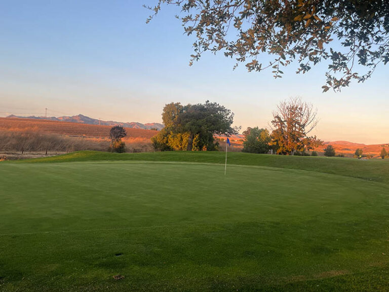Ridgemark Golf Club & Resort green with a flagstick, trees, and Hollister countryside views in the background.