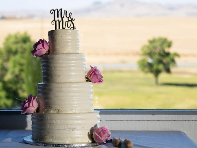Tiered wedding cake with pink roses and a Mr. and Mrs. topper overlooking the golf course.