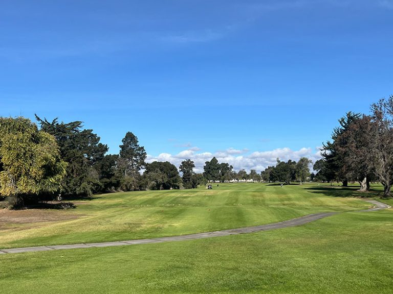 Tree-lined fairway and winding cart path stretching toward the green at Salinas Fairways Golf Course.